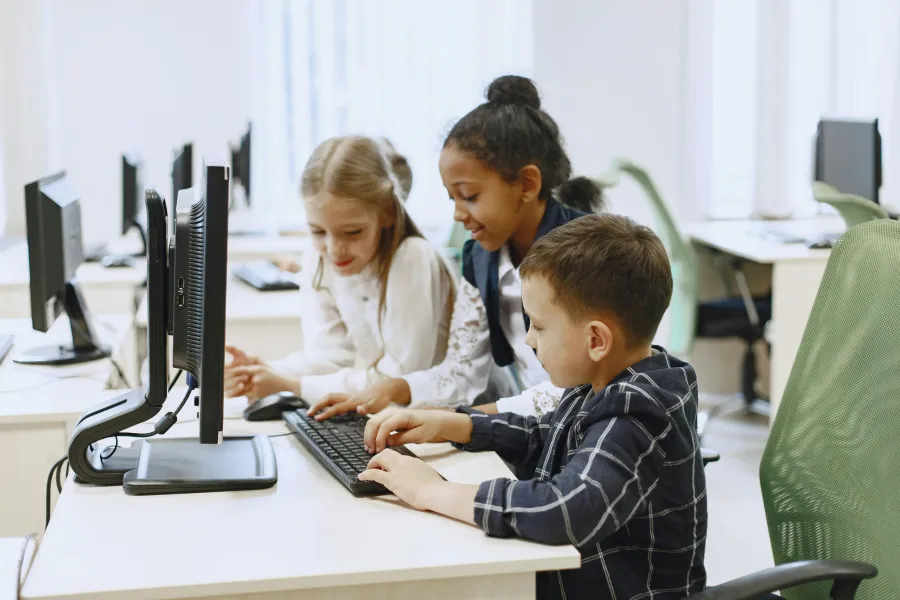 Children learning in a classroom, by working together on computers.